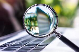 Magnifying glass showing computer keyboard keys being examined photo