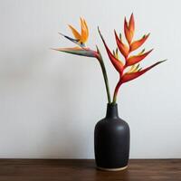 floral arrangement featuring bird of paradise flowers in a black ceramic vase placed on a wooden table against a neutral background photo