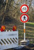 Park area with prohibitory road signs for pedestrians and bicycles. The fence restricts access to the closed area, elements of nature are visible in the background. photo