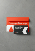 A red envelope mockup and a black and white name card mockup rest on a concrete surface psd