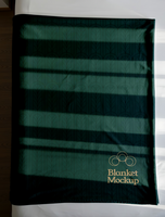 A dark green blanket with a subtle patterned design and Blanket Mockup subtly printed on it psd