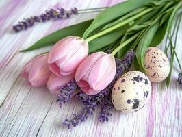 A bouquet of spring tulips and lavender and Easter eggs are lying on a wooden table. photo