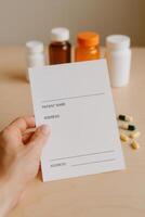Prescription form held by a hand with medicine bottles and capsules in soft focus background. Perfect for illustrating healthcare topics, pharmacy concepts, or clinical documentation visuals photo