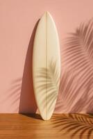 Retro-style cream surfboard leaning on a pastel pink wall with palm leaf shadows across the surface. Perfect for beach visuals, summer concepts, and stylish lifestyle branding photo