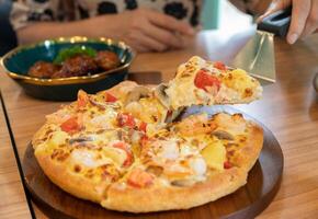 Someone using a pizza peel for separate a piece of pizza before eating. photo