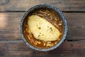 High angle view of Kare Udon topping with creamy omelet served on wooden table. photo
