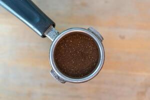 Ground coffee in portafilter on wood table photo