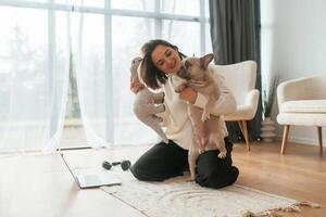 With toy, in hand. Young woman is with her pug dog at home photo
