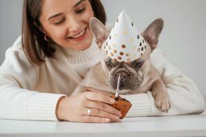 Happy ,birthday. Pet ,in ,hat and with cake. Young woman is with her pug dog at home photo