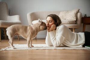 Looking at, each, other, lying down on floor. Young woman is with her pug dog at home photo