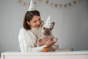 Celebration, of ,birthday.. In hats and with cake. Young woman is with her pug dog at home photo