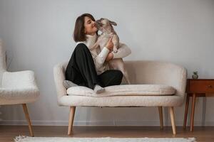 Sitting together. Young woman, is, with her pug dog at home photo