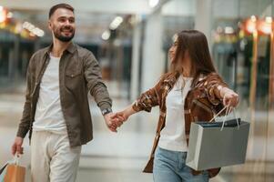 Guy don't ,want to go for shopping. Young couple are in supermarket together photo