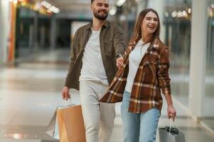 Guy don't want ,to ,go for shopping. Young couple are in supermarket together photo