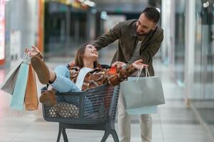 Riding in a shopping cart., Young ,couple are in supermarket together photo