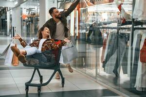 Cheerful, riding in the, cart. Young couple are in supermarket together photo