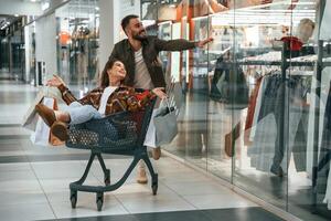 Cheerful,, riding in the cart. Young couple are in supermarket together photo
