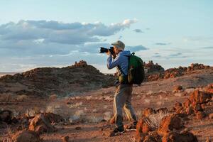 Using camera. Male tourist in, casua,l clothes is in the deserts of Africa, Namibia photo
