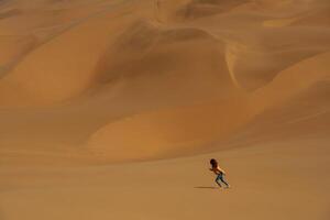 Distant view, of woman that is walking in the sands of Namibia, Africa desert photo