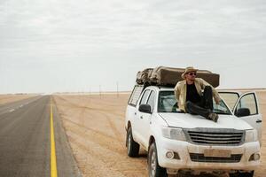 Man, tourist with car in the deserts of Africa, Namibia photo