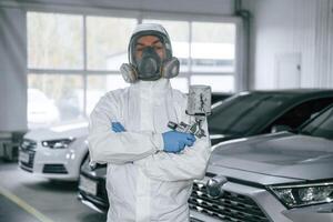 Customer ,,service. Man is standing and ,holding spray gun with paint for automobile photo