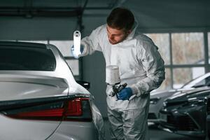 Rear,, part of automobile. Garage worker is holding lighting and checking surface of the car photo