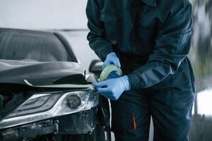Man is putting tape on, the, broken surface of the automobile photo