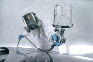 Close up view of man, that ,is painting a car by using spray guy photo
