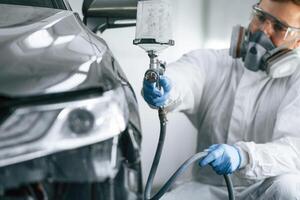 Man is painting ,a car by using spray guy photo