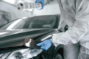 Choosing ,,right color. Garage worker is holding lighting and checking surface of the car photo