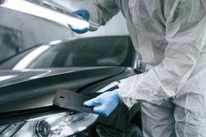 Choosing right ,color. Garage worker is holding lighting and checking surface of the car photo