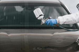 Close up view of man that ,is painting a car by using spray guy photo
