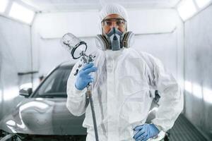 Customer ,service. Man is standing and holding spray gun with paint for automobile photo