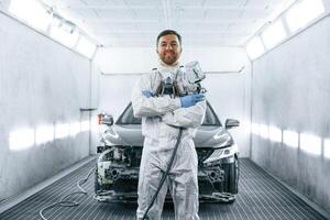 Man,, is standing and holding spray gun with paint for automobile photo