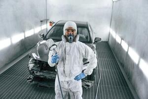 Customer service. Man, is, standing and holding spray gun with paint for automobile photo