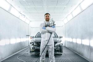 Man is, standing ,,and holding spray gun with paint for automobile photo