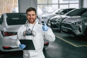 Portrait of car painter that is standing in the garage with ,,documents in hands photo