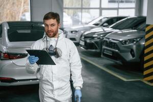 Positive facial ,expression. .Car painter is standing in the garage with documents in hands photo