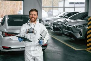 Portrait ,of,, car painter that is standing in the garage with documents in hands photo