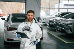 Car painter is standing in the,, garage ,with documents in hands photo