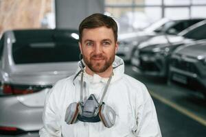 Portrait, of ,professional painter with mask that is standing in the garage with cars photo