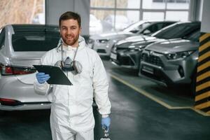 Positive ,facial ,expression. Car painter is standing in the garage with documents in hands photo