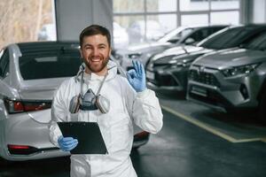 Portrai,t of car painter that is standing in the garage with documents in hands photo