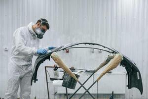 Side view. Repairman is working with ,,carcass of the car in the garage photo
