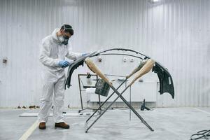 Side view. Repairman, is, working with carcass of the car in the garage photo