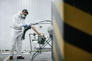 Side view. Repairman is, working with ,carcass of the car in the garage photo