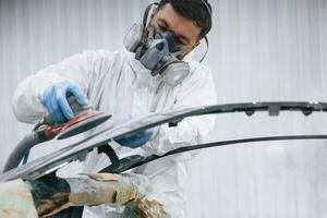 Polishing ,the surface. Repairman,is working with carcass of the car in the garage photo