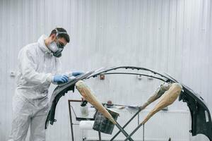 Unfinished part. Repairman ,,is working, with carcass of the car in the garage photo