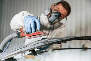 Polishing the surface. Repairman, is working with carcass of the car in the garage photo