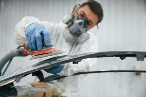 Polishing, the surface. Repairman is working with carcass of the car in the garage photo